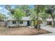 Inviting single-story home featuring a vibrant blue door, lush greenery, and a well-maintained front yard at 1041 Forest Grove Blvd, Palm Harbor, FL 34683
