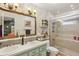 Well-lit bathroom featuring double sinks, a large framed mirror, and a glass door shower at 11849 Cedarfield Dr, Riverview, FL 33579