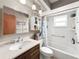 Well-lit bathroom with a shower-tub combination, white tiles, modern vanity and a cabinet for toiletries at 12125 71St Way, Largo, FL 33773