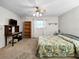 Cozy bedroom with a ceiling fan, carpet flooring, a desk and a queen-size bed covered with a patterned bedspread at 12125 71St Way, Largo, FL 33773