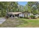 Charming ranch-style home featuring a stone facade and a lush, green front lawn surrounded by mature trees at 1221 Candlelight Blvd, Brooksville, FL 34601