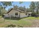 The back of the property showcases a charming, single-story home with a well maintained lawn surrounded by mature trees at 1221 Candlelight Blvd, Brooksville, FL 34601
