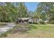 Charming ranch-style home featuring a stone facade and a lush, green front lawn surrounded by mature trees at 1221 Candlelight Blvd, Brooksville, FL 34601