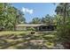 Back exterior of home featuring manicured lawn, screened patio, and mature trees, offering a private outdoor living space at 1221 Candlelight Blvd, Brooksville, FL 34601
