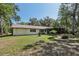Back exterior shows a spacious lawn, mature trees, and screened patio, offering a relaxing outdoor living at 1221 Candlelight Blvd, Brooksville, FL 34601