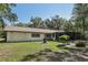 Charming home features a well-manicured lawn, screened in porch, and a mix of mature trees adding to the home's curb appeal at 1221 Candlelight Blvd, Brooksville, FL 34601