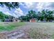 Wide backyard view featuring the house, screened-in pool, detached garage, and ample green space at 15302 Lake Maurine Dr, Odessa, FL 33556