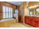 Bathroom showcases a soaking tub with plantation shutters and a tiled walk-in shower with mosaic accents at 15302 Lake Maurine Dr, Odessa, FL 33556