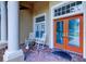 Inviting front porch with rocking chairs, brick flooring, and a beautiful entryway with an orange double door at 15302 Lake Maurine Dr, Odessa, FL 33556