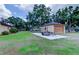 Detached garage with a trailer parked on a concrete pad, next to the main house and landscaping at 15302 Lake Maurine Dr, Odessa, FL 33556