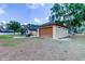 Detached garage with a brown door and tan siding, adjacent to the main house at 15302 Lake Maurine Dr, Odessa, FL 33556