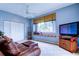 Comfortable living room with a leather couch, window seat, and a ceiling fan providing natural light at 15302 Lake Maurine Dr, Odessa, FL 33556