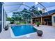 Beautiful in-ground pool with screened enclosure, brick patio, and lush tropical landscaping at 15302 Lake Maurine Dr, Odessa, FL 33556