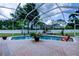 Screened-in pool with brick patio and view of the backyard and surrounding greenery at 15302 Lake Maurine Dr, Odessa, FL 33556