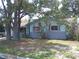 A one-story home featuring large windows, mature trees, and landscaping elements in the front yard at 212 Driftwood Pl, Palm Harbor, FL 34683