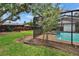 The screened pool area with a tile edge pool is surrounded by a green lawn and established landscaping at 2413 Buckhorn Run Dr, Valrico, FL 33596