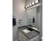 Modern bathroom with a granite countertop, decorative mirror, and stylish lighting fixture at 2823 Banyan Hill Ln, Land O Lakes, FL 34639