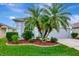 Charming curb appeal featuring a well-manicured lawn, vibrant landscaping, and mature palm trees at 2823 Banyan Hill Ln, Land O Lakes, FL 34639