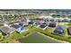 An aerial showcases properties with pools and lanais, positioned by a peaceful pond, in a well-planned community setting at 34266 Radley Way, Wesley Chapel, FL 33545