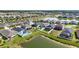 An aerial showcases properties with pools and lanais, positioned by a peaceful pond, in a well-planned community setting at 34266 Radley Way, Wesley Chapel, FL 33545