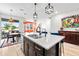 Open-concept kitchen island with dark cabinets, pendant lighting, and views into the living and dining areas at 34266 Radley Way, Wesley Chapel, FL 33545