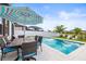 Enjoy the poolside dining area with a large patio umbrella in this backyard at 34266 Radley Way, Wesley Chapel, FL 33545