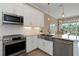 Well-lit kitchen boasts stainless appliances, white cabinets, and a view into the dining and living area at 4139 Rocky Shores Dr, Tampa, FL 33634