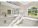 Bright bathroom featuring double vanity, sleek fixtures, and a freestanding tub under an arched window at 4227 Sandy Shores Dr, Lutz, FL 33558