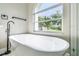 Modern bathtub with a black faucet positioned beneath a large window view of the landscaped yard at 4227 Sandy Shores Dr, Lutz, FL 33558