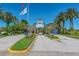 Main entrance of a community with palm trees, landscaped greenery, and a clear blue sky at 4227 Sandy Shores Dr, Lutz, FL 33558