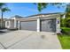 Three-car garage with gray doors and a concrete driveway of a modern home at 4227 Sandy Shores Dr, Lutz, FL 33558
