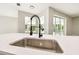 Modern kitchen sink with stainless steel fixtures and quartz countertops overlooking a bright sunroom at 4227 Sandy Shores Dr, Lutz, FL 33558