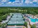 Aerial view of multiple tennis courts and a swimming pool with a slide and ample surrounding lush trees at 4227 Sandy Shores Dr, Lutz, FL 33558