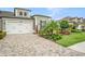 Charming home with brick driveway, two-car garage and tropical landscaping with green lawn at 4329 Barletta Ct, Wesley Chapel, FL 33543