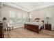 This main bedroom features a wooden bed frame, tray ceiling, and wood-look tile flooring at 4329 Barletta Ct, Wesley Chapel, FL 33543