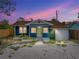 Charming blue home with a yellow door, lush greenery, and a spacious gravel driveway at 4727 17Th S Ave, St Petersburg, FL 33711