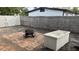 Backyard featuring a brick patio with a fire pit and a storage box, enclosed by a wooden fence for privacy at 4735 W Oklahoma Ave, Tampa, FL 33616