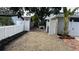 Gravel driveway leading to a fenced backyard with a view of a patio, offering ample space for parking at 4735 W Oklahoma Ave, Tampa, FL 33616