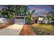 Charming one-story home with a red door, well-manicured lawn, tropical landscaping, and driveway at 4735 W Oklahoma Ave, Tampa, FL 33616
