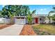 Charming one-story home with a red door, well-manicured lawn, tropical landscaping, and driveway at 4735 W Oklahoma Ave, Tampa, FL 33616