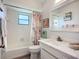 The bathroom features a modern vanity, seashell-themed shower curtain, and a white-tiled shower adding coastal charm to the space at 5456 Fairway Bend Dr, Sarasota, FL 34243