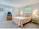 Cozy bedroom showcases floral bedding and a wicker dresser beneath a bright window, complemented by matching bedside tables at 5456 Fairway Bend Dr, Sarasota, FL 34243