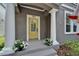 Charming front porch with yellow door, white columns, and decorative flower pots at 5914 Goldenbark Pl, Lithia, FL 33547