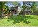 Lush backyard featuring a covered porch, mature trees, and ample green space for outdoor activities and relaxation at 6501 Barcellona Rd, Land O Lakes, FL 34637