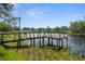 Scenic lake view with a wooden dock, clear water, and lush vegetation, offering a serene waterfront experience at 6501 Barcellona Rd, Land O Lakes, FL 34637