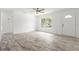 Sunlit living room featuring wood-look tile flooring and a welcoming front door at 6620 Del Prado Ter, New Port Richey, FL 34652