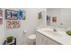 Powder room with a white sink, toilet, mirror, and decorative wall art at 745 Pinellas Bayway S # 206, St Petersburg, FL 33715