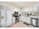 Bright kitchen featuring white cabinets, stainless steel appliances, and neutral tile flooring at 745 Pinellas Bayway S # 206, St Petersburg, FL 33715