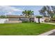 A well-kept single-story home featuring a beautiful, green lawn and palm trees at 7851 120Th St, Seminole, FL 33772