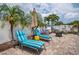 Relax on the sunny brick patio featuring lounge chairs, palm trees, and a cozy fire pit area perfect for outdoor gatherings at 7851 120Th St, Seminole, FL 33772